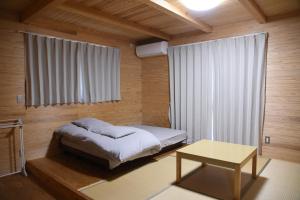 1 dormitorio con cama, mesa y ventana en Wakka, en Minami Aso
