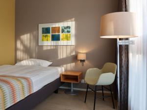 una camera con letto, sedia e lampada di Hotel Berchtold a Burgdorf