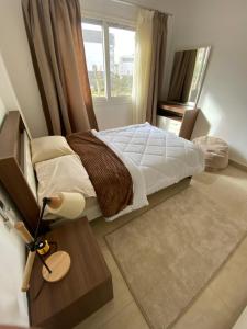 1 dormitorio con 1 cama y 1 mesa con lámpara en Madinaty Well-furnished 3- Bedroom apartment - شقة فندقيه للايجار مدينتي, en Madīnat ash Shurūq