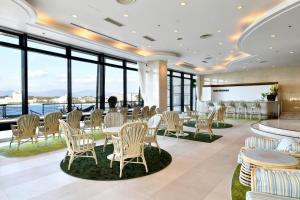 a dining room with tables and chairs and large windows at The Gran Resort Elegante Shirahama in Shirahama