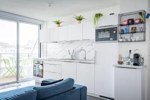 une cuisine avec des placards blancs et un canapé bleu dans l'établissement L'Académie - Terrasse avec vue - Parking, à Strasbourg 19 autres photos