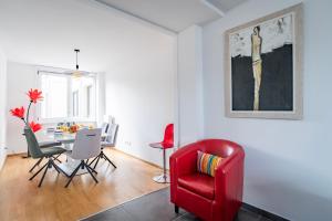 - un salon avec une chaise rouge et une table dans l'établissement L'Académie - GOLDEN TREE - Parking Privé & Wifi - 5 min centre ville de Strasbourg, à Strasbourg