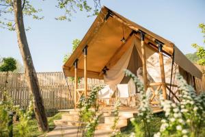 a tent with a porch and chairs in a garden at Villaggio Camping Odissea in Marina di Camerota