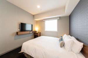 a bedroom with a white bed and a flat screen tv at Tokyu Stay Sapporo Odori in Sapporo