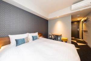 a bedroom with a large white bed with blue pillows at Tokyu Stay Sapporo Odori in Sapporo