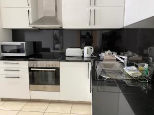 eine Küche mit weißen Schränken und einem Geschirrspüler in der Unterkunft Icon Luxury Apartments in Kapstadt