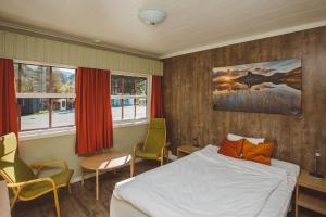 1 dormitorio con 1 cama, sillas y ventanas en Saltdal Turistsenter en Storjord