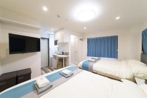 Habitación de hotel con 2 camas y TV de pantalla plana. en High Five Guest House, en Tokio