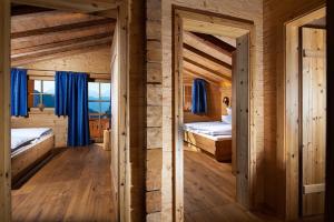 two beds in a wooden room with blue curtains at Ettlerlehen Chalets in Ramsau
