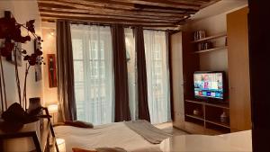 una camera con un letto e una televisione di fronte a una finestra di Gorgeous Paris St Germain des Près a Parigi