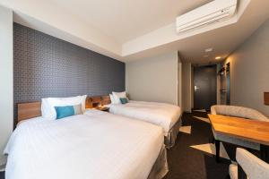 a hotel room with two beds and a table at Tokyu Stay Sapporo Odori in Sapporo