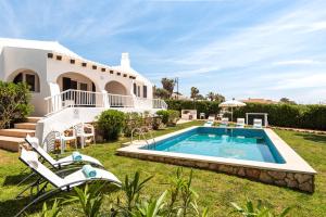 a villa with a swimming pool in front of a house at Villa BiniRe in Binibeca