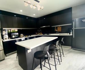 una cocina con armarios negros y una barra con taburetes en 燕旅宿 en Neipu