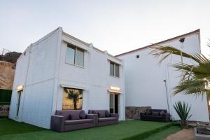 a white house with two couches in a yard at منتجع قرية الفقرة in As Sudayrah