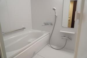 a white bath tub sitting next to a white sink at Hotel WBF Sapporo Chuo in Sapporo