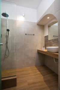 a bathroom with a shower with a sink and a mirror at Muses Hotel in Faliraki