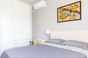 - une chambre blanche avec un lit et une photo sur le mur dans l'établissement Trilocale colline di Bardolino, à Bardolino