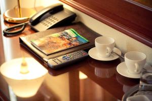 a table with two cups and a phone and a book at Kristoff Hotel in Saint Petersburg