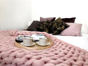 a bed with a pink blanket and two tea cups on it at Apartament Litevski Deluxe in Lublin