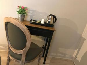 una mesa con una silla y una maceta de flores. en Hôtel de charme Equinoxe, en Le Touquet-Paris-Plage