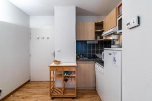 a small kitchen with a white refrigerator and a table at Les Jardins de Ramel - Apt proche des pistes avec Wifi in Luchon