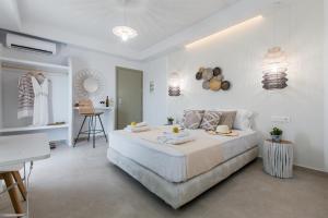 a white bedroom with a large bed and a table at LEMONIA STUDIOS&SUITES in Agia Anna Naxos