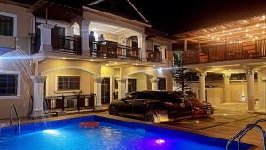 a car parked in front of a house with a swimming pool at Yussals Apartments in Kokrobite