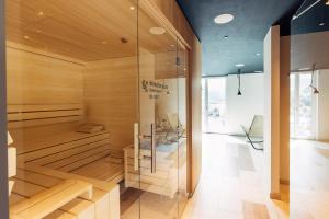 a sauna with wooden walls and a glass wall at harry's home hotel & apartments in Bischofshofen