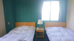 twee bedden naast elkaar in een slaapkamer bij Bayside Hotel Ryugu / Vacation STAY 63714 in Anan