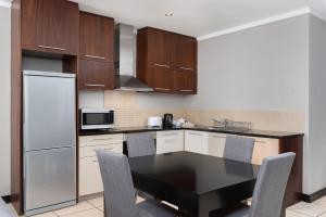 a kitchen with a refrigerator, stove, microwave and a table at Icon Luxury Apartments in Cape Town