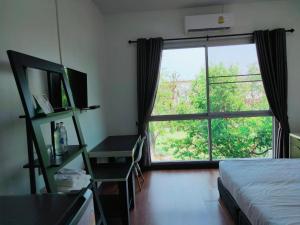 a bedroom with a bed and a large window at TaamJai Resort in Nakhon Phanom