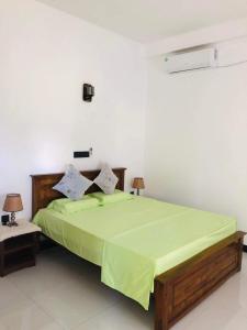 a bedroom with a bed with a green comforter at Mirissa Paddy House in Mirissa