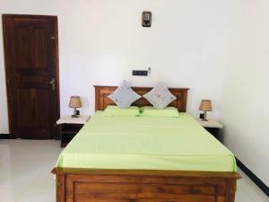 Mirissa Paddy House في ميريسا: غرفة نوم مع سرير مع شراشف خضراء ومصباحين