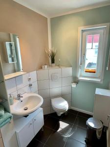 a bathroom with a sink and a toilet and a window at Ferienzimmer/wohnung am Kurstrand, WLAN in Zingst +8 photos