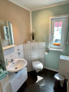 a bathroom with a sink and a toilet and a window at Ferienzimmer/wohnung am Kurstrand, WLAN in Zingst