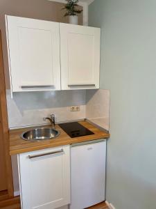 a small kitchen with white cabinets and a sink at Ferienzimmer/wohnung am Kurstrand, WLAN in Zingst