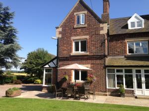 a brick house with chairs and an umbrella at Whitethorn Bed and Breakfast in Congleton