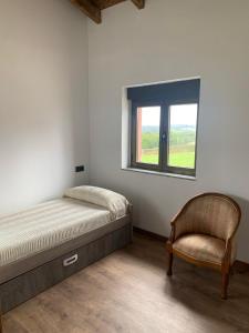 a bedroom with a bed and a chair and a window at Casa Lin Nieva in Nieva