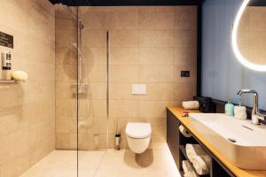 uma casa de banho com um chuveiro, um WC e um lavatório. em harry's home hotel & apartments em Bischofshofen
