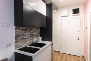 a kitchen with black and white cabinets and a sink at Room Jacuzzi “ATHENA” in Subotica