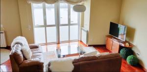 ein Wohnzimmer mit einem Sofa und einem TV in der Unterkunft Graña Beach Ferrol in A Coruña