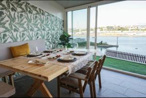 ein Esszimmer mit einem Tisch und einem großen Fenster in der Unterkunft Graña Beach Ferrol in A Coruña