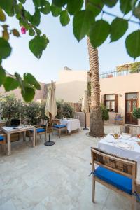 a patio with tables and umbrellas and a palm tree at La Maison Ottomane in Chania Town