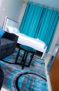 a bed in a room with a couch and a stool at Maven Glow Elegant Studios in Kiambu