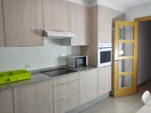 a kitchen with wooden cabinets and a microwave and a refrigerator at the sanxi apt in Lugo