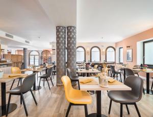um restaurante com mesas, cadeiras e janelas em Rivalta Life Style Hotel em Salò