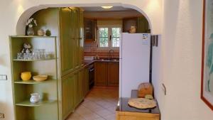 Una cocina con gabinetes verdes y un refrigerador blanco. en ROCAS ROJAS OCEAN VIEW SAN AGUSTIN, en San Agustín