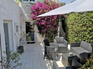 um pátio com cadeiras, um guarda-sol e flores cor-de-rosa em Appartement 50 m2 dans une maison privative avec terrasse et jardin privée em Le Cannet