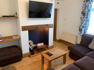 a living room with a fireplace with a tv on the wall at The Cottage At The Retreat in Leek