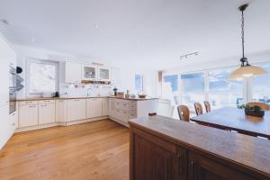 a kitchen with white cabinets and a table with chairs at Panorama Chalet Schmittendrin by we rent, SUMMERCARD INCLUDED in Zell am See